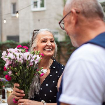 anniversary captions woman smiling to man and holding a bouquet of flowers