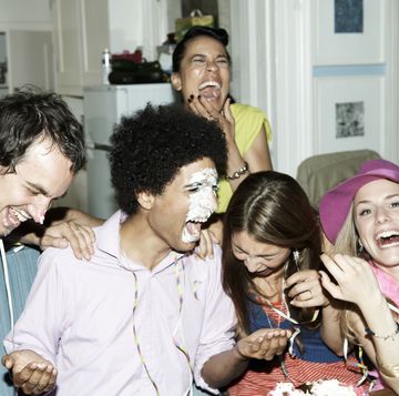 birthday jokes  man with icing on his face laughing with a group of friends
