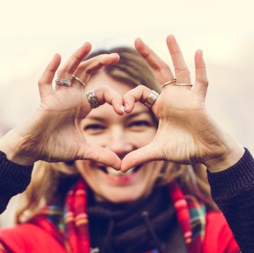 smiling woman shows a heart shaped gesture