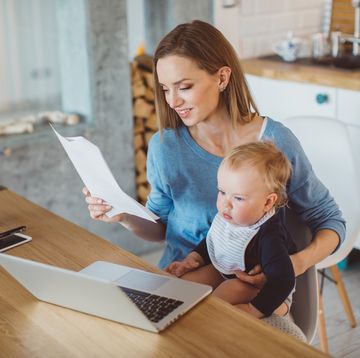 best stay at home mom jobs woman holding baby while looking at paperwork and laptop