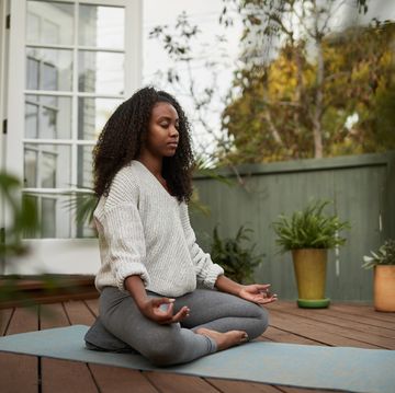 young woman sitting in the lotus pose outside on her patio